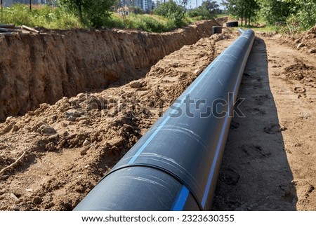 Large industrial black plastic polypropylene modern sanitary pipe on the construction site for laying water pipes, construction and reconstruction of buildings and houses. Royalty-Free Stock Photo #2323630355