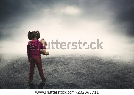 Little girl with toy bear in the darkness