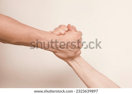 Two hands hold tightly to each other, rescuer saves, pulls out of trouble a person in need of help, the concept of helping someone in need, selective focus Royalty-Free Stock Photo #2323639897