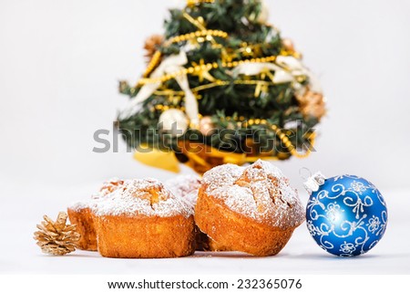 Muffins, cone, Christmas ball and tree in background. Shallow depth of field