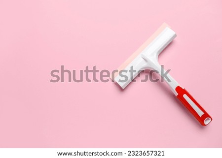 White plastic squeegee on pink background Royalty-Free Stock Photo #2323657321