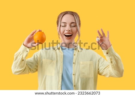 Young woman with soluble tablet and orange on yellow background
