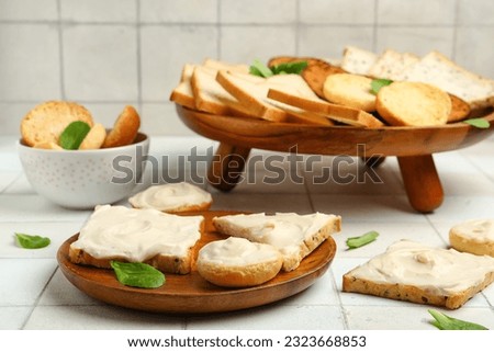 Plate of tasty toasts with cream cheese on white tile background Royalty-Free Stock Photo #2323668853