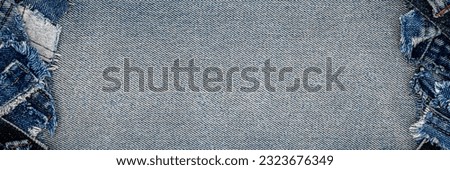 Panoramic Denim blue jeans fabric frame. Ripped denim cloth. Destroyed torn denim blue jeans patches, banner background. Recycle old jeans denim pieces concept. Royalty-Free Stock Photo #2323676349
