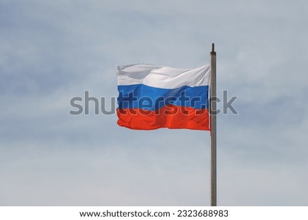 Photography of the national flag of the Russian Federation in front of the sky. White clouds, blue sky.  Tricolor. Red, Blue, White stripes. Politics concept. Close up panoramic photography. 