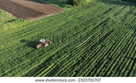 Agricultural field aerial view. Tractor taking care of the product on field. Selective focus included. Drone view.