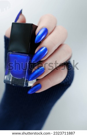 Woman's beautiful hand with long nails and bright blue manicure