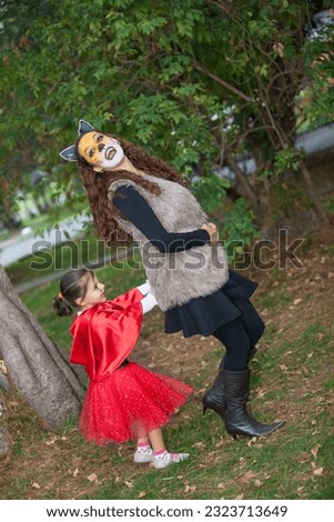 Beautiful girl on little red riding hood costume playing with her mom. Real family having fun while using costumes of the Little red riding hood tale in Halloween.