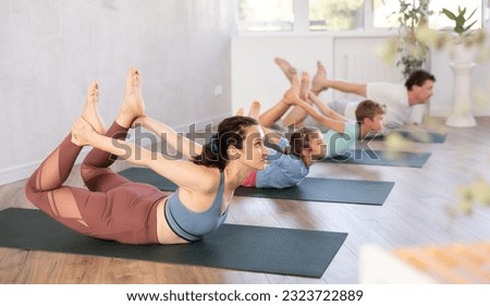 Family with daughter and son practice yoga poses in fitness class
