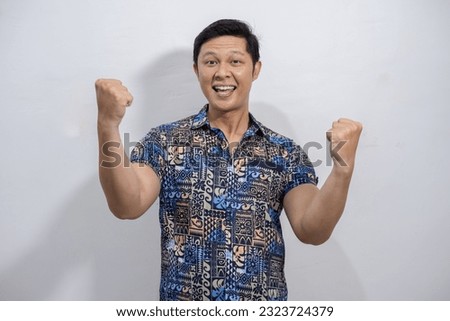 Young asian man wearing colorful abstract patterned shirt smiling and happy with yes gesture, yes expression, success over something