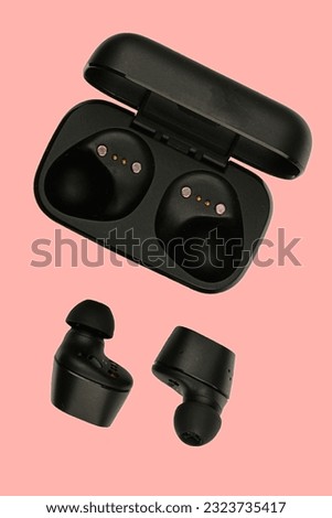 Wireless stereo earbuds. Black wireless earphones and charging case. Earbuds or headphones and charging case with bult-in rechargeable battery for the earbuds isolated on pink background with clipping
