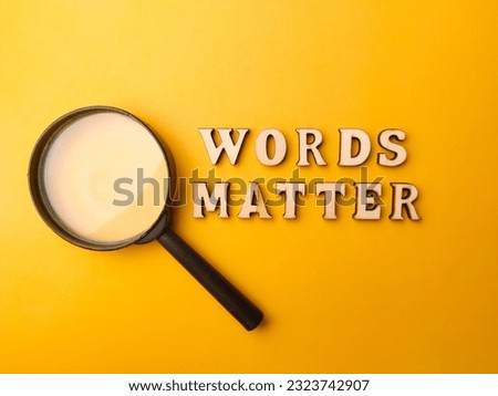 Magnifying glass and wooden letter toy arranged the word WORDS MATTER with a yellow background.