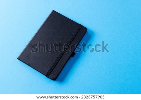 Close up of black notebook with copy space on blue background. Literature, reading, writing, leisure time and books.