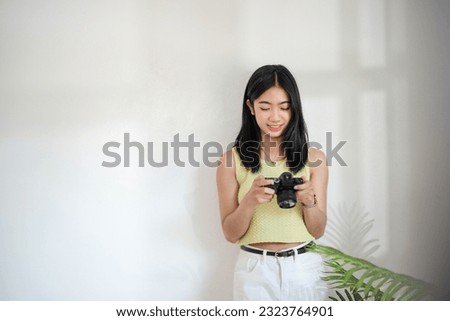 Asian creative woman looking on her camera.
