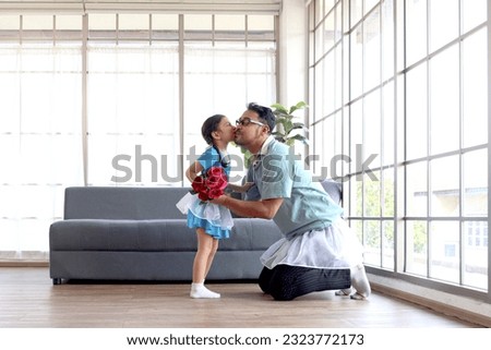 Cute little girl kissing her cheerful handsome dad after dancing together and daddy giving flower bouquet, dad trying to train daughter to dance ballet, family spend time together. Happy Father Day.