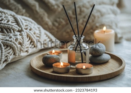 Home aroma diffuser with fresh sea breeze fragrance, stones, pebbles and shells as decor on table in the bedroom. Cozy relaxing atmosphere, knitted pillows, burning candles. Aromatherapy Royalty-Free Stock Photo #2323784193