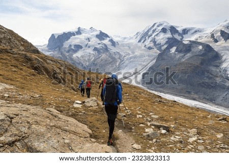 Panorama view with mountain Dufourspitze (left), Gorner Glacier, mountain Lyskamm (right) and group of mountaineers hiking towards mountain massif Monte Rosa in Pennine Alps, Switzerland Royalty-Free Stock Photo #2323823313