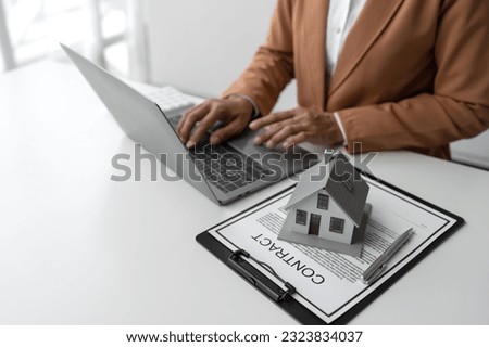 Real estate, home buying concept, real estate agent typing house purchase contract documents and bank loans for buying selling houses and land.