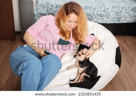 woman at home with a phone shopping online, stroking a dog, internet banking, online training, social networks and instant messengers Royalty-Free Stock Photo #2323851435