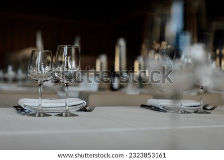 Luxury table settings for fine dining with and glassware, pouring wine to glass. Beautiful blurred background. Preparation for holiday wedding. Fancy luxury restaurant.
