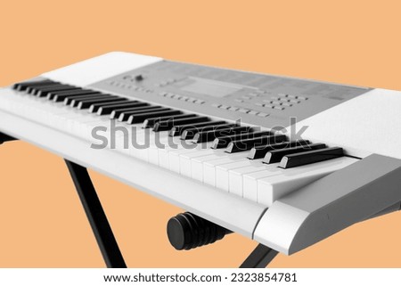 Modern synthesizer on beige background, closeup