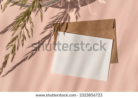 Empty paper card mockup, envelope, meadow grass with sunlight shadow on a light peach neutral background. Aesthetic wedding invitation, postcard template