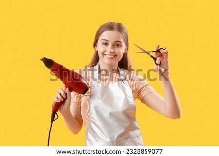 Female hairdresser with dryer and scissors on yellow background Royalty-Free Stock Photo #2323859077