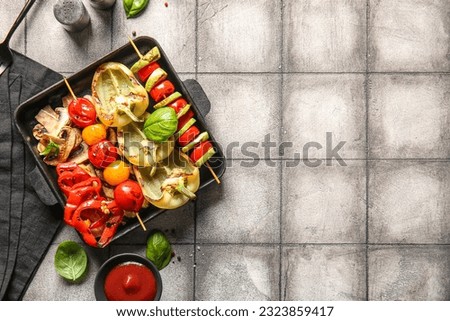 Baking dish with tasty grilled vegetables on grey tile background