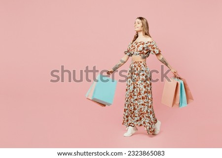 Full body young side view woman wears summer casual clothes hold in hand paper package bags after shopping walk go isolated on plain light pastel pink background. Black Friday sale buy day concept