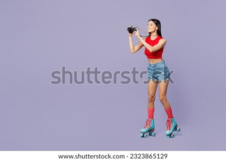 Full body side view young latin woman she wear red casual clothes rollers rollerblading taking photo on photocamera isolated on plain pastel purple background. Summer sport lifestyle leisure concept
