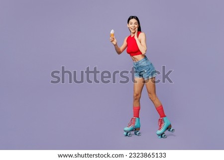 Full body side view surprised amazed young latin woman wear red casual clothes rollers rollerblading eat ice-cream isolated on plain pastel purple background. Summer sport lifestyle leisure concept.