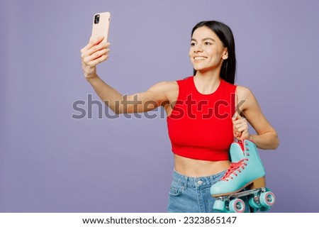 Young latin woman wear red casual clothes hold in hand rollers doing selfie shot on mobile cell phone isolated on plain pastel purple background studio portrait. Summer sport lifestyle leisure concept