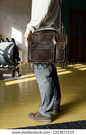 Part photo of a man with a brown leather briefcase with antique and retro look. indoors photo