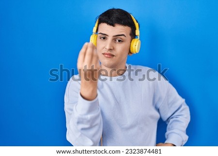 Non binary person listening to music using headphones doing italian gesture with hand and fingers confident expression 