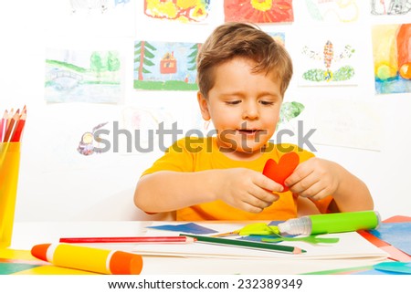 Happy small boy crafting heart shaped carton