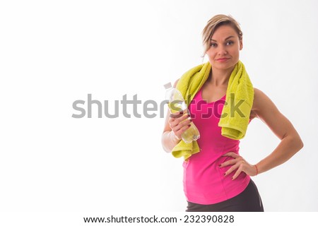 Beautiful, athletic blonde posing on a white background with a towel around his neck and a bottle of water in hand. Sports, fitness, exercise, beautiful figure - the concept of a healthy lifestyle.