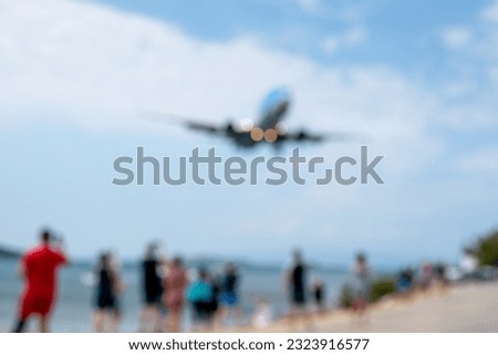 An airliner about to land at an airport. A crown of people take pictures as it descends.Fully blurred picture, ideal as a concept or background image. Copy space.