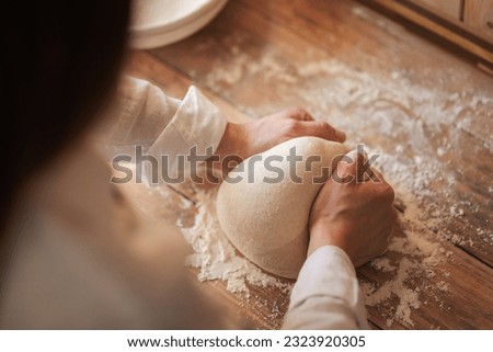 Female baker kneads dough, making tasty and airy bread by herself. Girl baking handmade bread at home Royalty-Free Stock Photo #2323920305