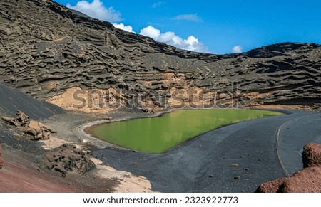 Green Lagoon or Charco de los Clicos. The green coloration is due to sulfur and algae. It is the crater of a volcano that has been invaded by the ocean. Also formed by a black sand beach. Royalty-Free Stock Photo #2323922773