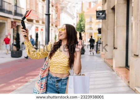 Stylish beauty woman waving during a video call walking on the street