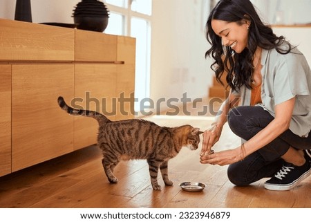 Smiling latin woman feeding her hungry cat at home. Pet lover hispanic woman giving food to cute domestic cat at home. Hapy girl feeding her pet with stew meal, domestic life with pet. Royalty-Free Stock Photo #2323946879