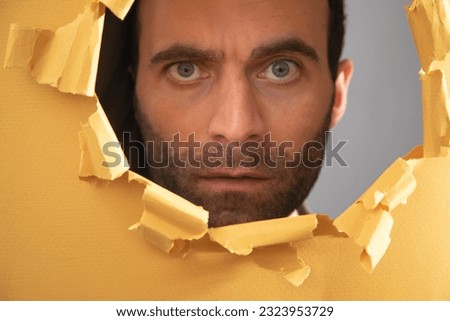 Man looking through hole in paper.