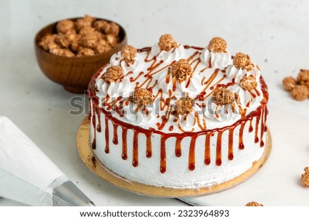 top view sweet cake with cream and liquid caramel next to full plate with chocolates Royalty-Free Stock Photo #2323964893