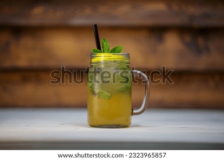 A closeup shot of a yellow cocktail in a glass decorated with mint leaves on a white surface