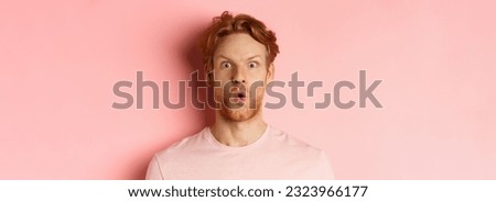Headshot of young redhead man with beard, saying wow and staring at camera amazed, checking out promo deal, standing over pink background. Royalty-Free Stock Photo #2323966177