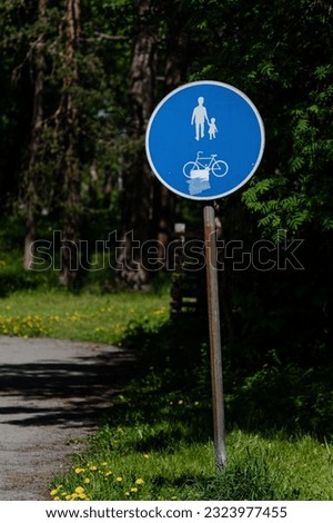 A vertical shot of a blue pedestrian and cyclist traffic sign by a path