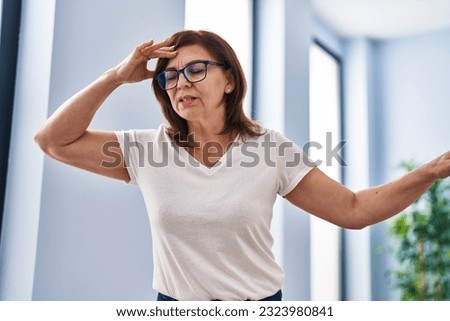 Middle age woman suffering dizzy standing at home Royalty-Free Stock Photo #2323980841
