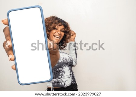 young african woman showing her phone screen excitedly Royalty-Free Stock Photo #2323999027