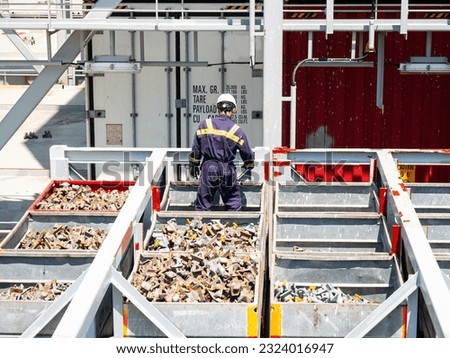 Crew member seaman in boiler suit and safety helmet painting metal construction gear box on container ship Royalty-Free Stock Photo #2324016947