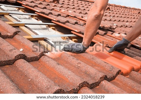 man replaces broken roof shingles on the rooftop with new ones. closeup shot, picture section with only the arms